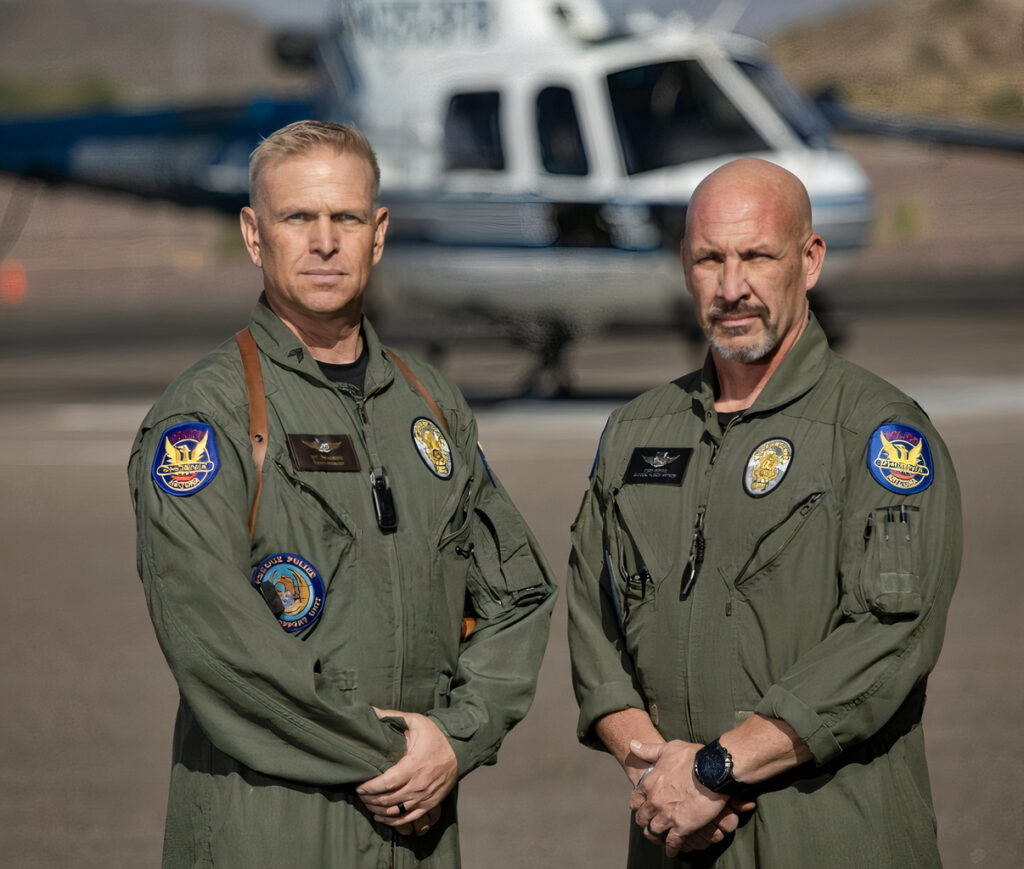 Two Phoenix Police from Air Support stand in their air support uniform in front of a helicopter.