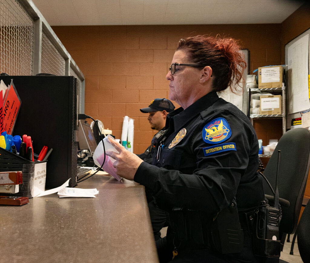 A PHX PD detention officer sitting at a desk.