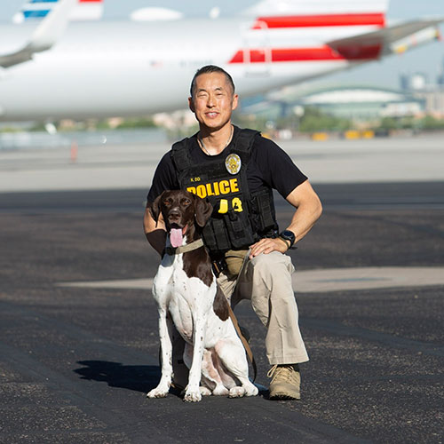 PHX PD police officer with a dog in front of an airport.