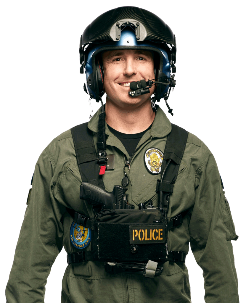 A man in an air support police uniform with the PHX PD is smiling and wearing a helmet.