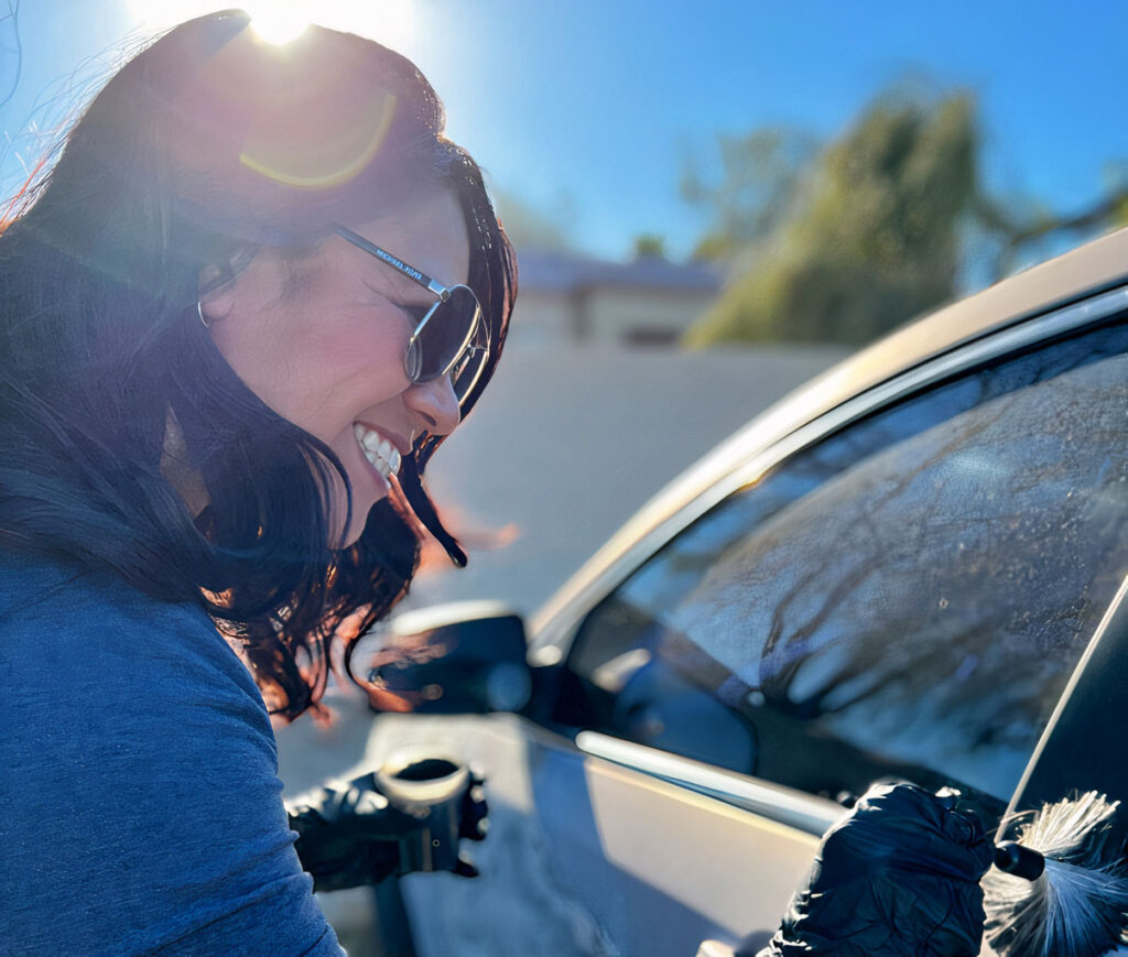 A civilian investigator with the PHX PD meticulously dusts a car window with a brush for fingerprints.